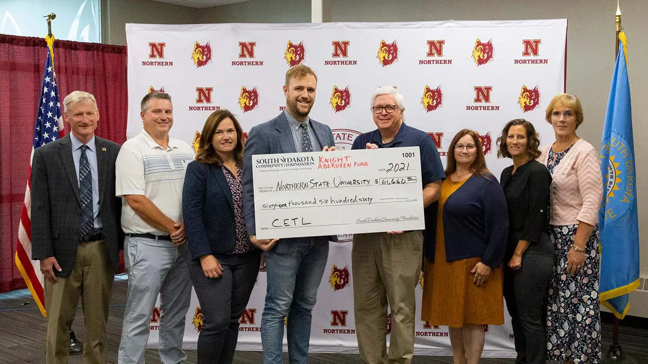 Staff holding giant check